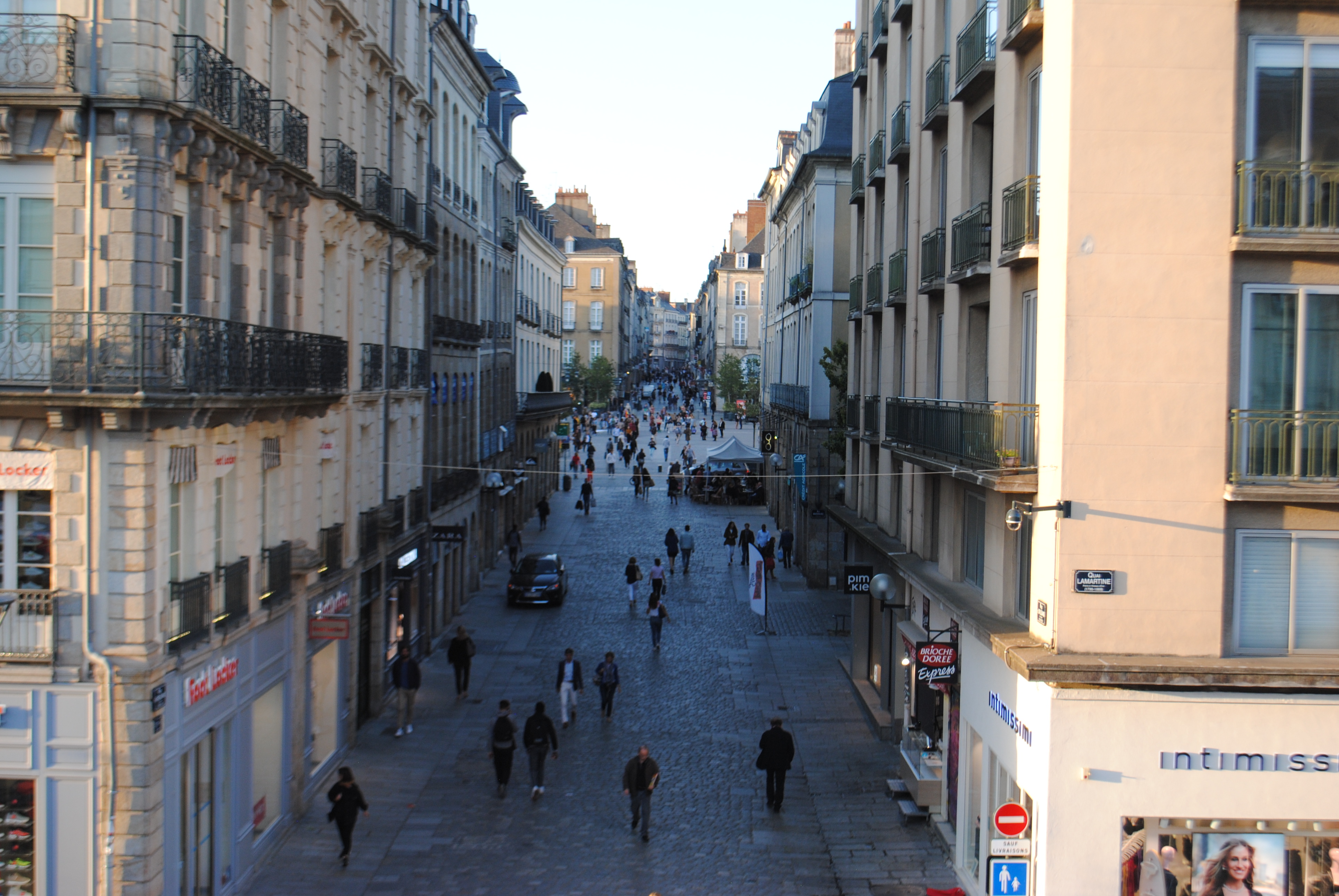 view of street between tall buildings with shops on the ground level