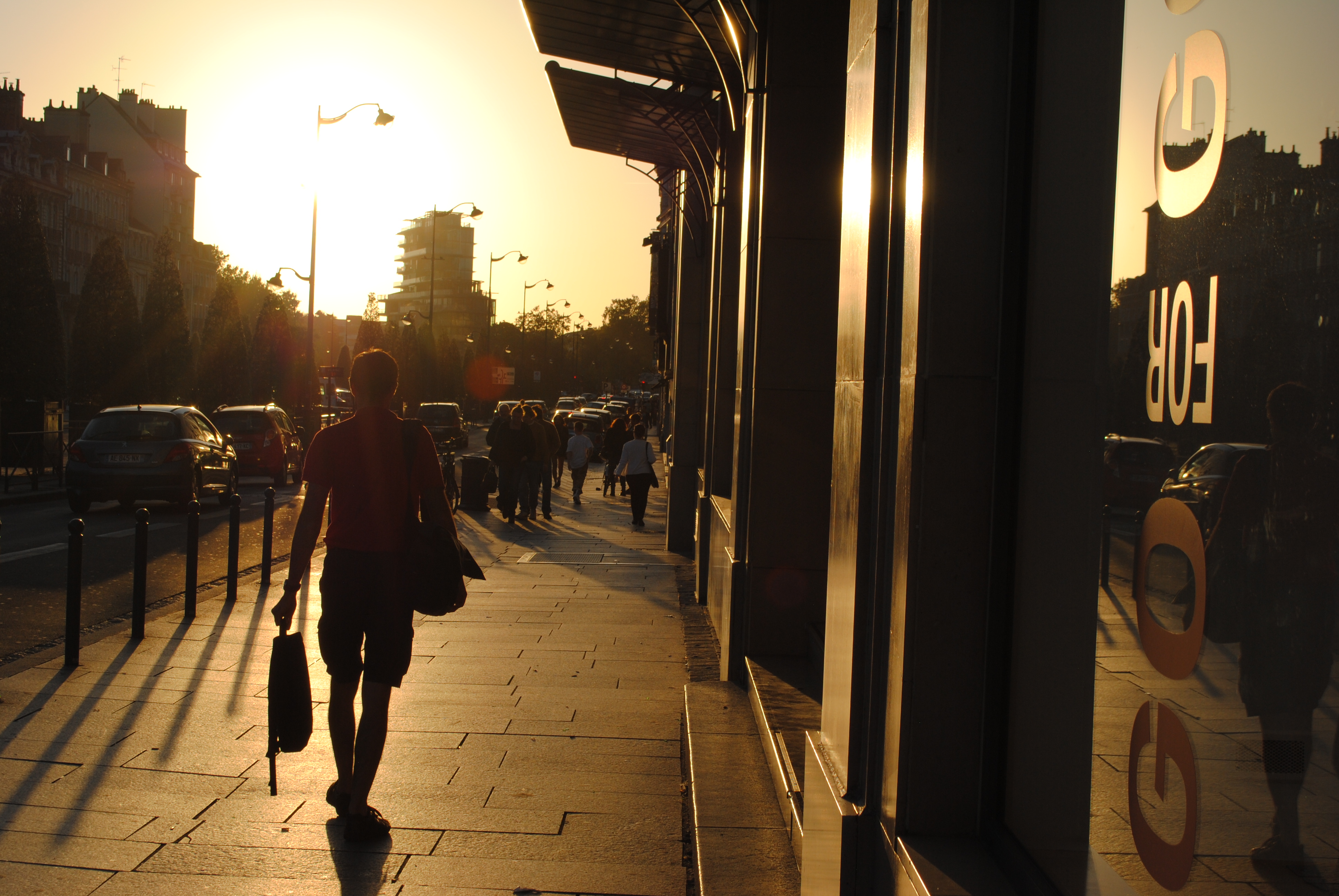 person walking on a street illuminated by setting sun 