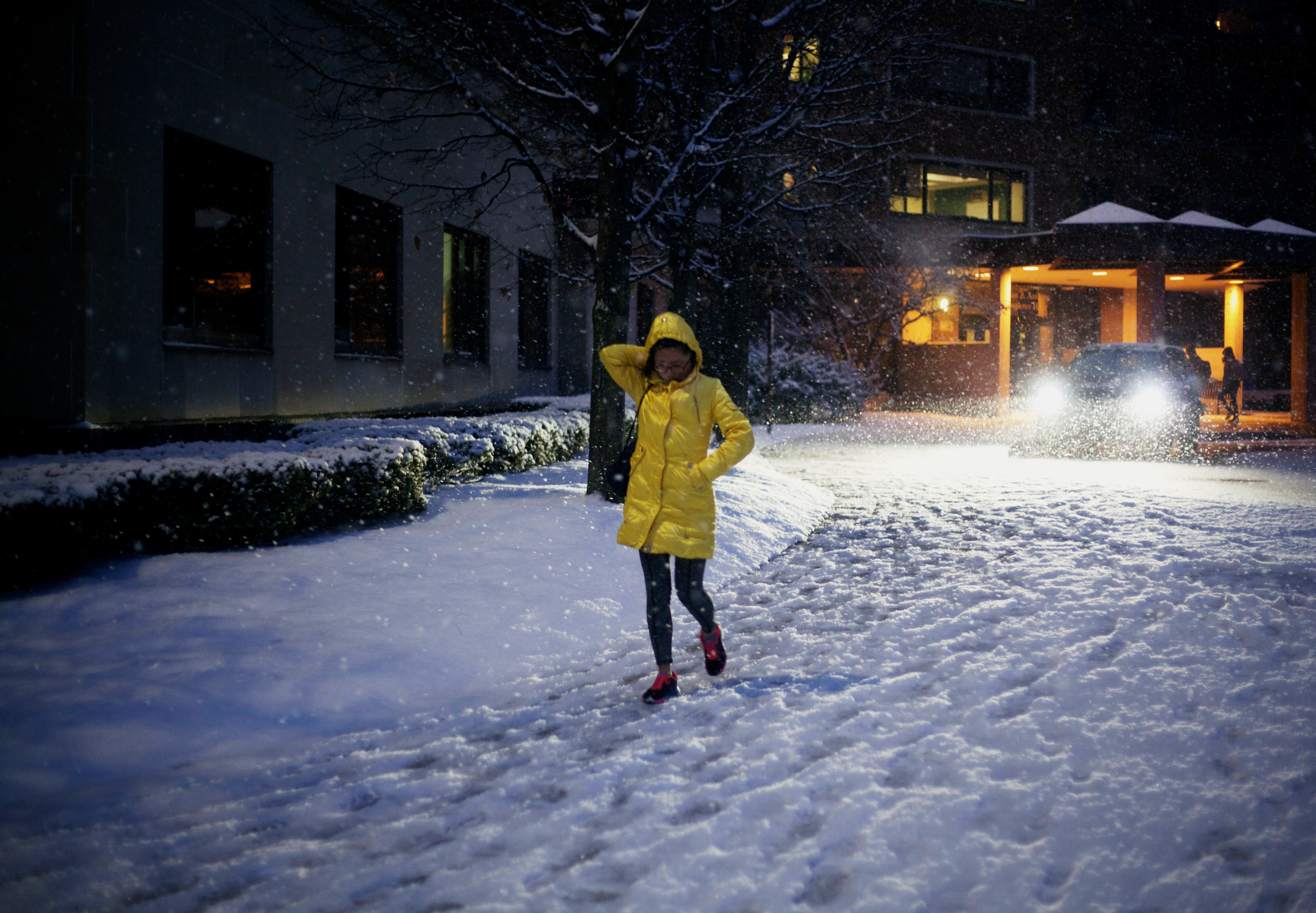 girl in yellow coat walking on a snow covered path