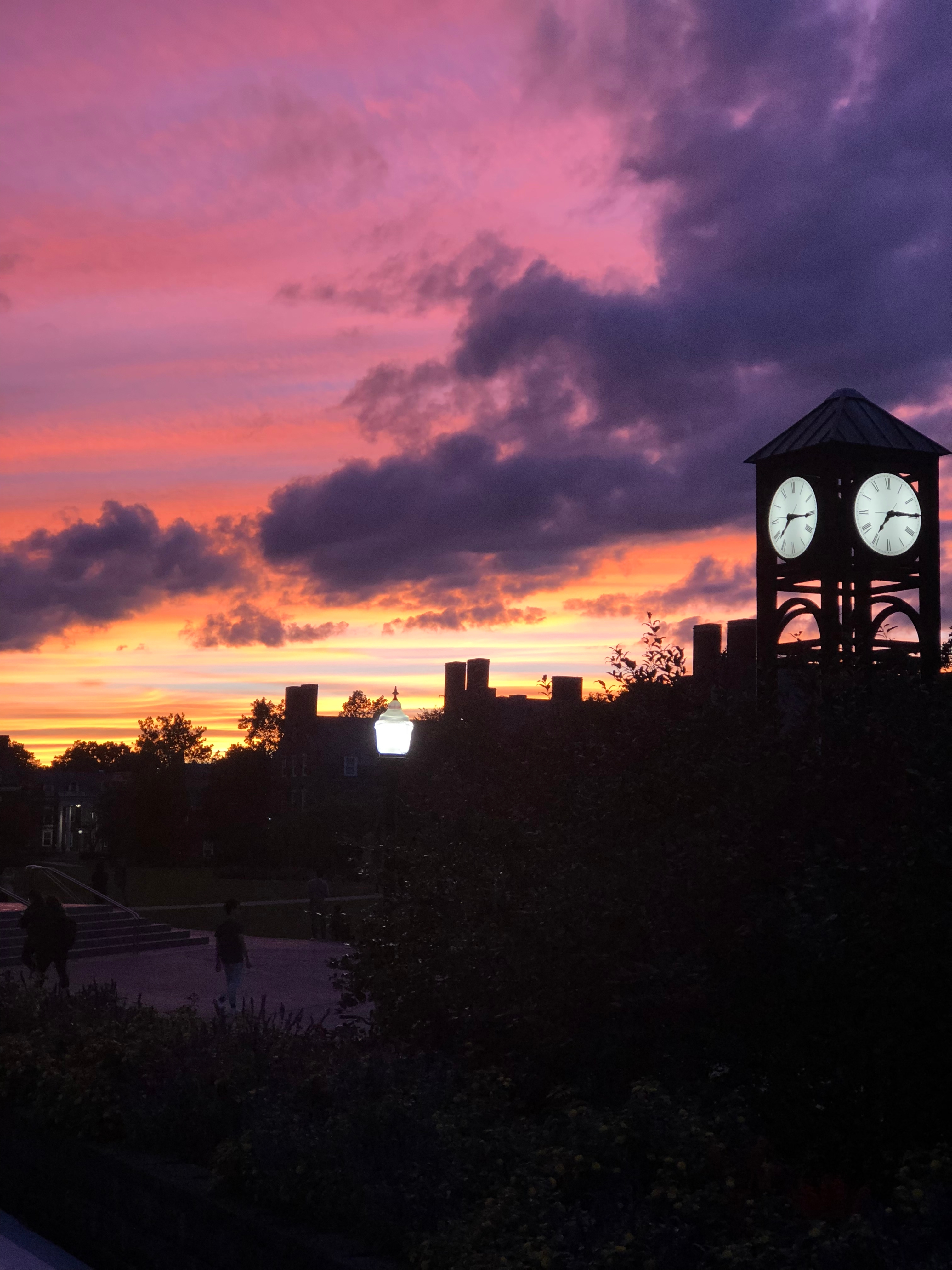 university of rochester clock tower and buildings silhouetted against sunset