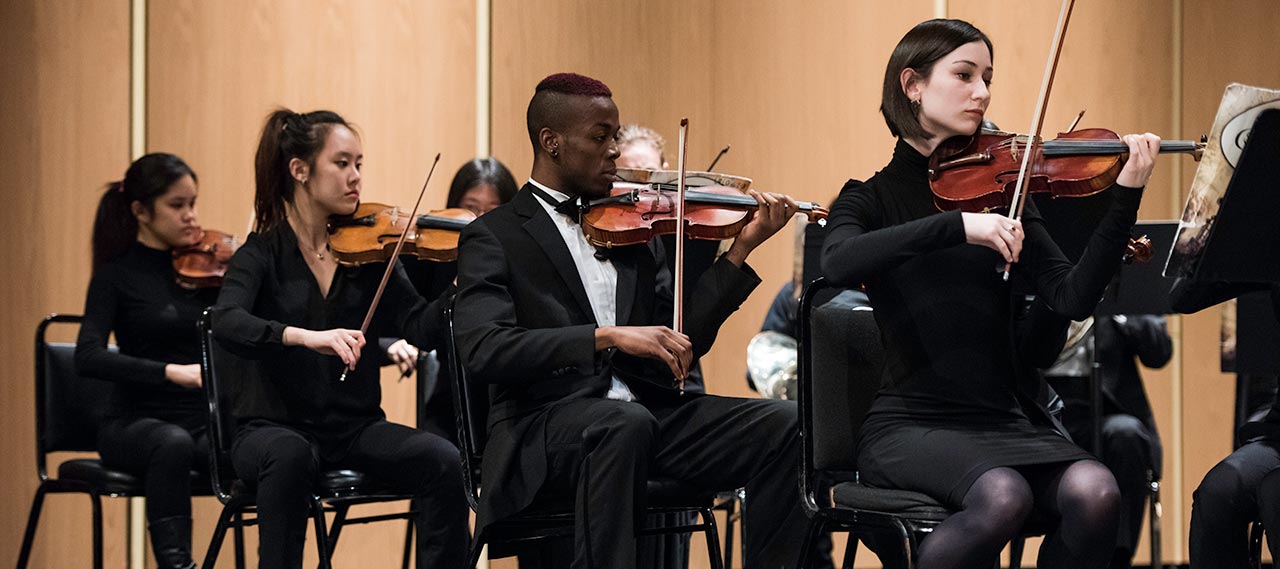 Three students playing violins.