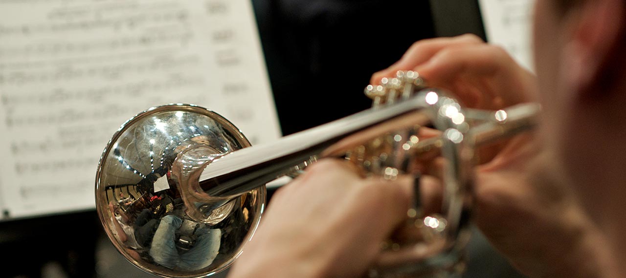 A close up of a student playing a trumpet.