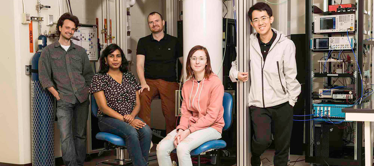Physics and astronomy professor Machiel Blok (middle) and PhD students (L-R) Ray Parker, Mihirangi Medahinne, Liz Champion, and Zihao Wang, in front of the dilution refrigerator in Blok’s lab.