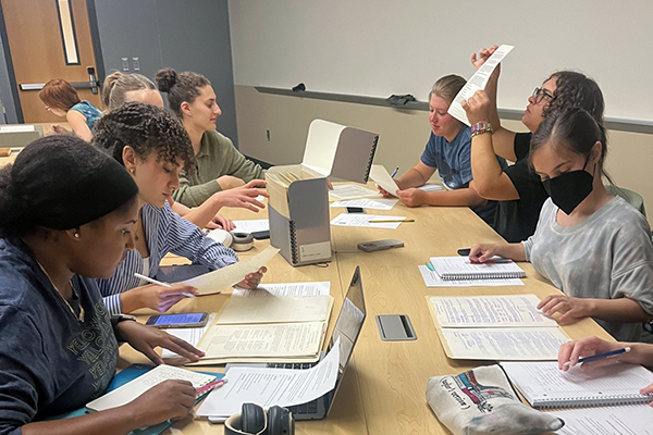 A group of students sit at a table reviewing health policy documents.