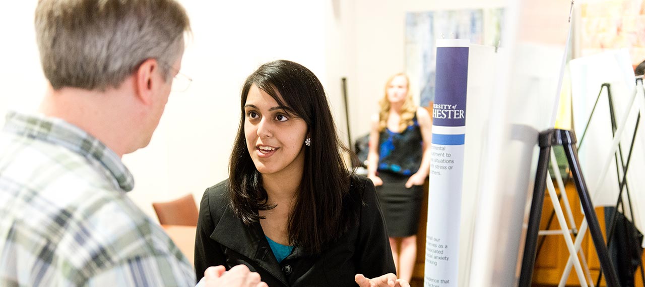 A student speaking to a professor at a poster session.