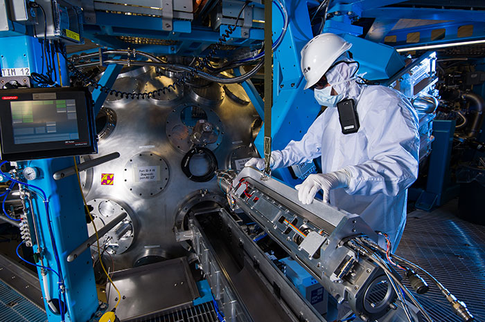 A technician maneuvers a diagnostic outside the target chamber of the Omega EP laser.