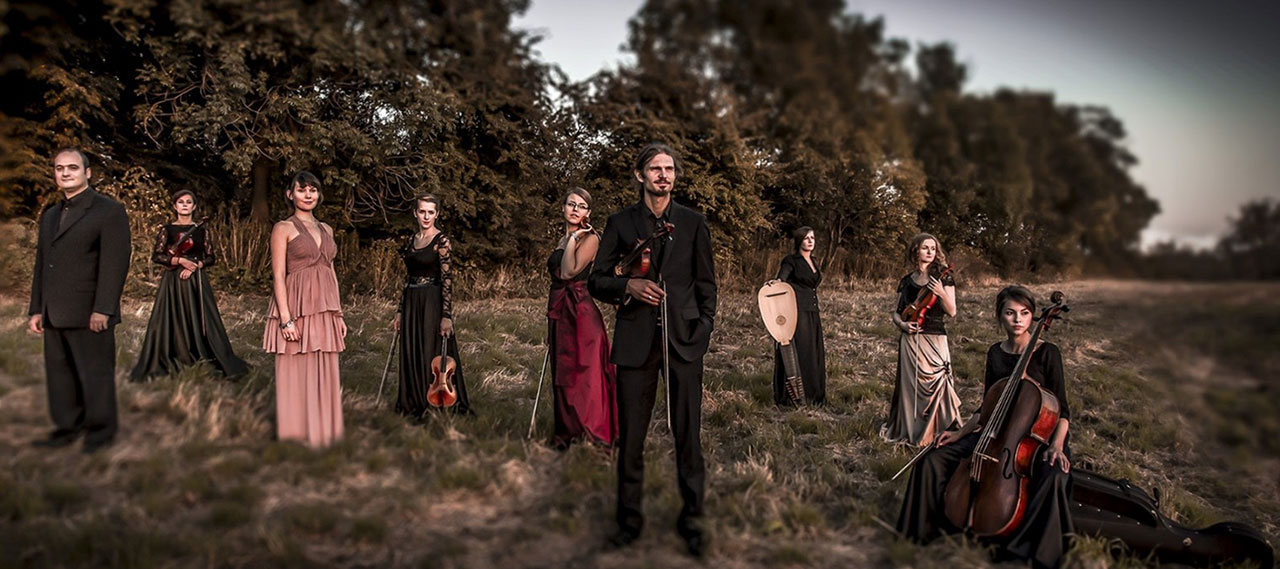 A group photo of the band standing in a meadow with their instruments.