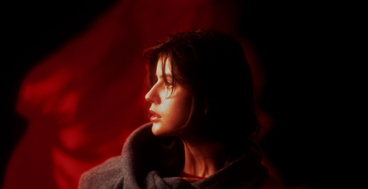 A still image from the movie of the side of a woman's face with a red background.