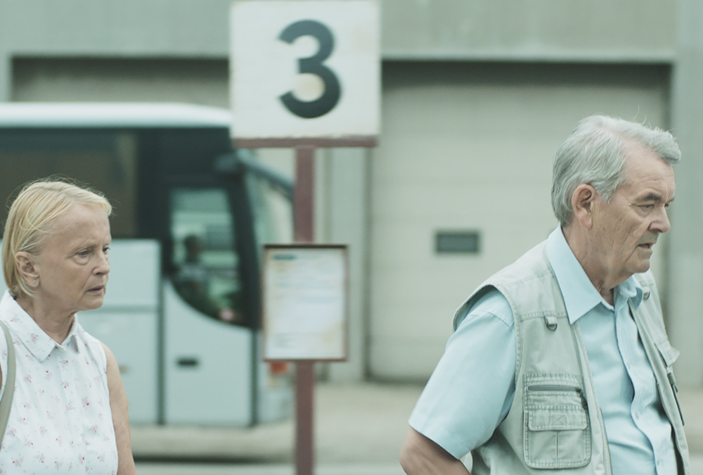 A still image from the movie of a man and woman walking across a parking lot.