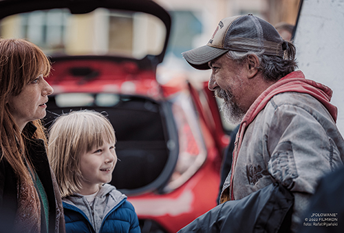 A still image from the film of a man speaking with a woman and a young boy.