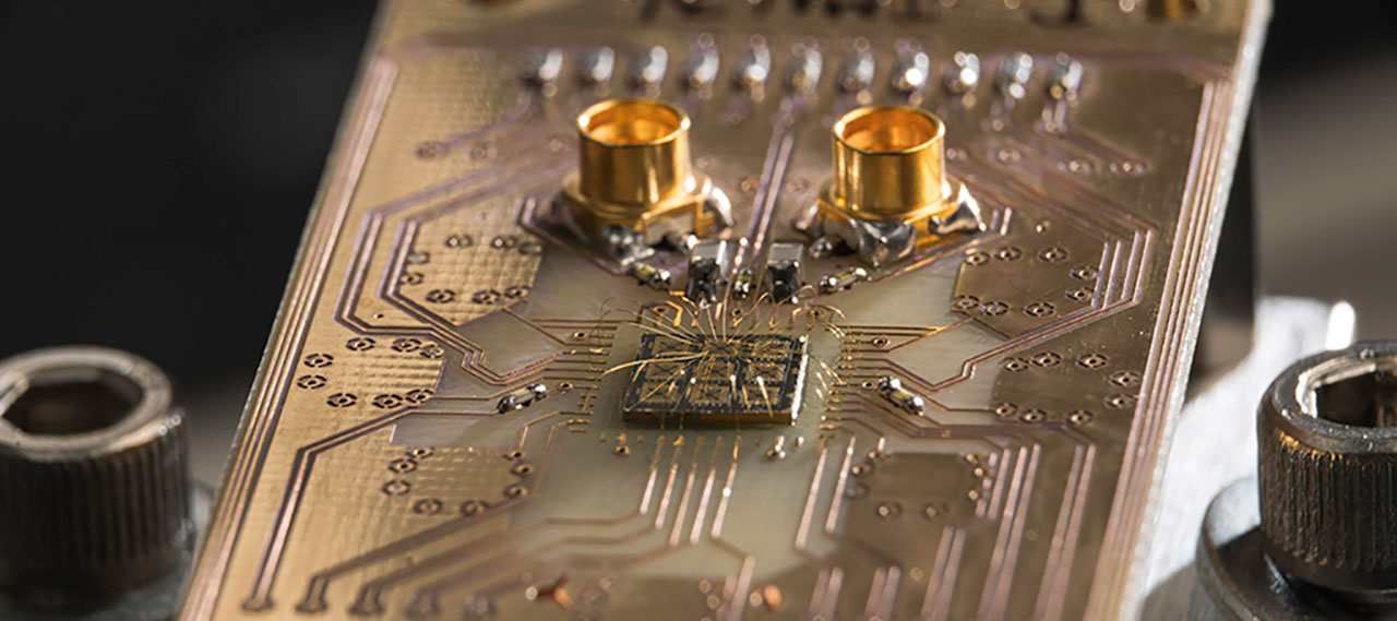A quantum processor semiconductor chip is shown connected to a circuit board.
