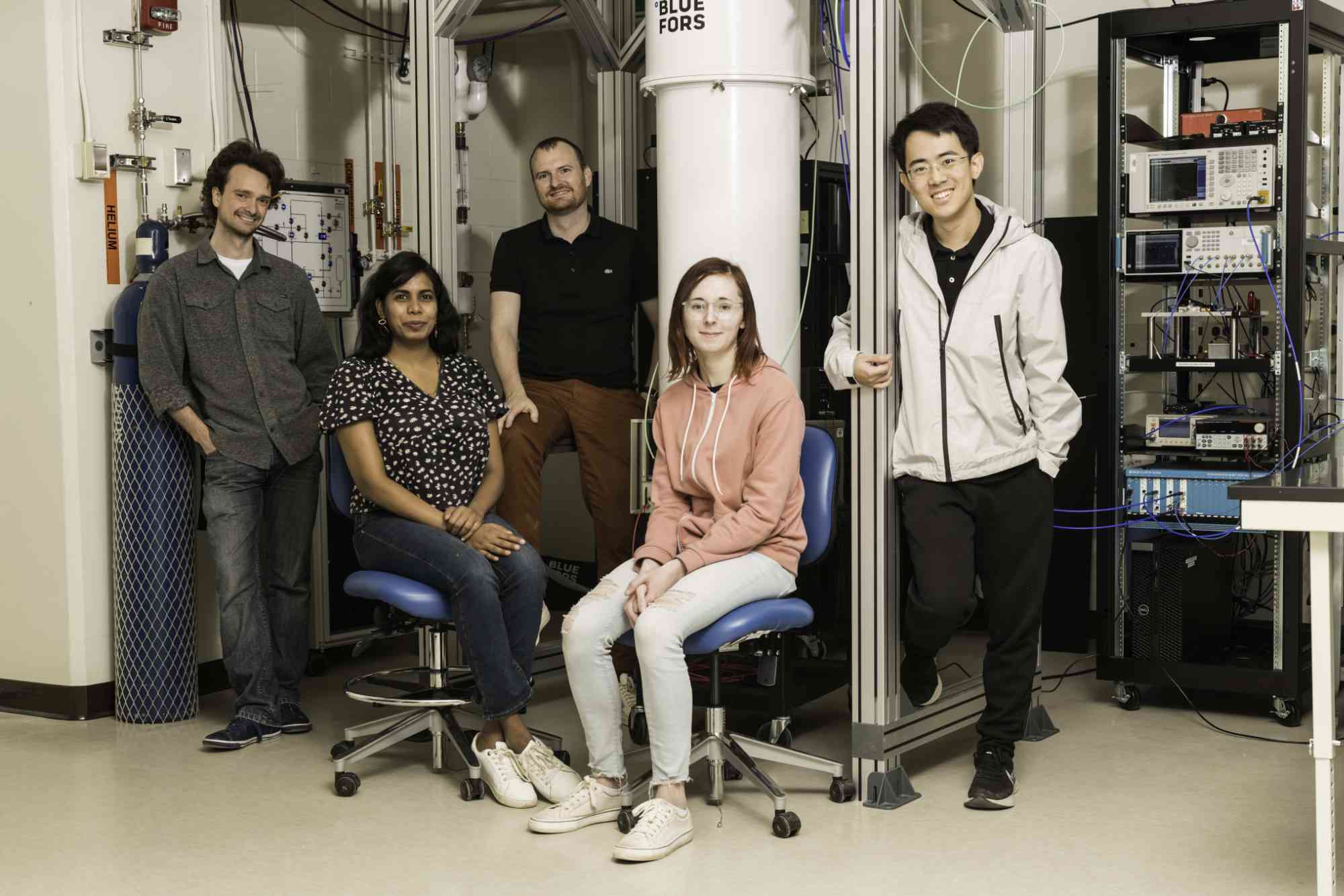 Physics and astronomy professor Machiel Blok (middle) and PhD students (L-R) Ray Parker, Mihirangi Medahinne, Liz Champion, and Zihao Wang, in front of the dilution refrigerator in Blok’s lab.